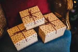 verpackte geschenkboxen liegen auf sessel. vorbereitete Überraschung zum Geburtstag oder einem anderen Feiertag. horizontales Bild von drei Präsentkartons mit Bändern. feier- und feiertagskonzept. foto