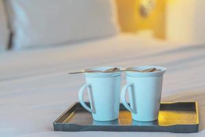 Nahaufnahme einer Doppel-Begrüßungskaffeetasse auf einem weißen Bett im Hotelzimmer - Hotel gut Gastfreundschaft Urlaubsreisekonzept foto