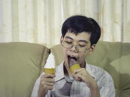 Asia Boy Kid hält Vanilleeis in Waffelkegeln glücklich lächelnd und isst im Sommer köstlich mit Spaß und guter Laune. foto