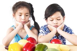 asiatische Jungen und Mädchen zeigen Abneigung Ausdruck mit frischem buntem Gemüse isoliert auf weißem Hintergrund foto
