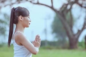 junge Dame, die Yoga-Übungen im Außenbereich der grünen Wiese macht und Ruhe und Frieden im Meditationsgeist zeigt - Menschen praktizieren Yoga für Meditations- und Übungskonzept foto