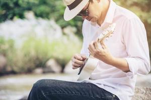 mann spielt ukulele neu im lebensstil der flussmenschen und musikinstrumente im naturkonzept foto