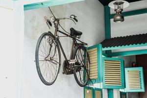 Altes Retro-Fahrrad, das neben Vintage-Fenstern an der Wand hängt. foto