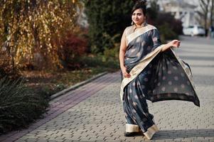 Elegantes brünettes südasiatisches indisches Mädchen im Saree zu Fuß im Freien. foto