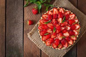 Torte mit Erdbeeren und Schlagsahne, dekoriert mit Minzblättern foto