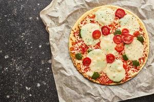 Fast Food gebackene Tiefkühlpizza mit Käse, Tomaten und Pesto. fertig für den Verzehr. foto