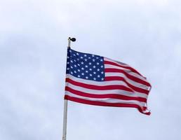 USA-Flagge an einem Fahnenmast, der sich langsam im Wind gegen den Himmel bewegt foto