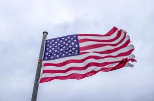 USA-Flagge an einem Fahnenmast, der sich langsam im Wind gegen den Himmel bewegt foto