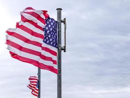 USA-Flagge an einem Fahnenmast, der sich langsam im Wind gegen den Himmel bewegt foto