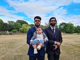 2 junge asiatische Männer gehen mit einem Kleinkind im örtlichen öffentlichen Park von luton england uk spazieren foto
