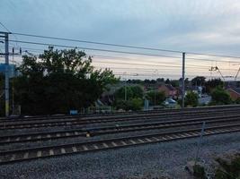 Luftaufnahmen Hochwinkelansicht der Stadt Luton in England und des Bahnhofs und des Zuges auf Gleisen bei Sonnenuntergang foto