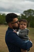 Der asiatische pakistanische Vater hält sein 11 Monate altes Kind im örtlichen Park foto