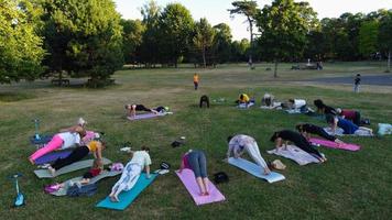 Gruppe von Frauen, die gemeinsam Yoga im öffentlichen Park bei Sonnenuntergang des heißen Sommers ausüben, Luftaufnahme aus dem hohen Winkel des Wardown Park Luton England Großbritannien foto