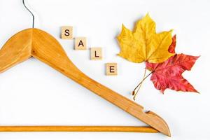Herbstverkauf und Rabatt. Kleiderbügel, gelbe Blätter und leere Etiketten auf weißem Hintergrund. Konzept für Werbung. foto