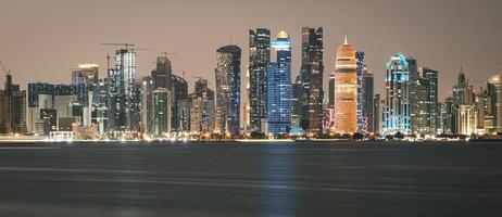 doha katar skyline bei nacht, die wolkenkratzerlichter zeigen, die sich im arabischen golf spiegeln foto