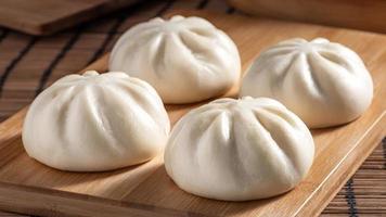 köstliches baozi, chinesisches gedämpftes fleischbrötchen ist essfertig auf servierplatte und dampfgarer, nahaufnahme, kopierraum produktdesignkonzept. foto