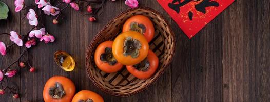 Draufsicht auf frische süße Persimonen mit Blättern auf Holztischhintergrund für das chinesische Neujahrsfest foto