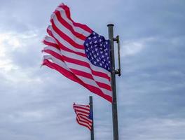 USA-Flagge an einem Fahnenmast, der sich langsam im Wind gegen den Himmel bewegt foto