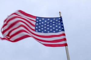 USA-Flagge an einem Fahnenmast, der sich langsam im Wind gegen den Himmel bewegt foto