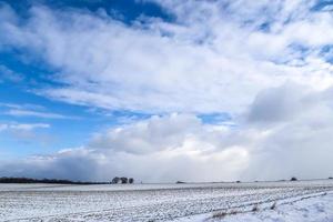 Schöne Wolken am Himmel mit Blick auf ein schneebedecktes landwirtschaftliches Feld. foto