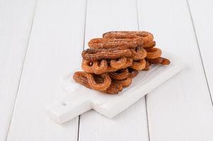 Hausgemachte Churros auf weißem Holzhintergrund. foto