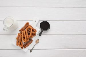 hausgemachte Churros mit Schokolade auf weißem Holzhintergrund. foto