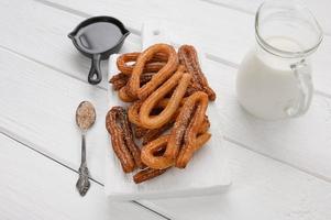 hausgemachte Churros mit Schokolade auf weißem Holzhintergrund. foto