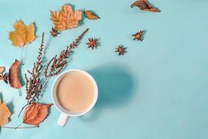 Herbstkomposition. tasse kaffee, herbstblätter, zimtstangen und anissterne auf hellblauem pastellhintergrund. flache Lage, Kopierraum von oben. foto