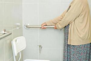 asiatische ältere alte patientin benutzt toilettenstützschiene im badezimmer, handlauf-sicherheitshaltegriff, sicherheit im pflegekrankenhaus. foto