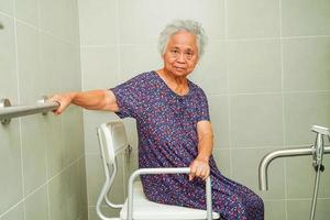 asiatische ältere alte patientin benutzt toilettenstützschiene im badezimmer, handlauf-sicherheitshaltegriff, sicherheit im pflegekrankenhaus. foto