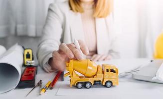 Zwei Kollegen diskutieren über Datenverarbeitung und Tablet, Laptop mit einem Architekturprojekt auf der Baustelle am Schreibtisch im Büro foto