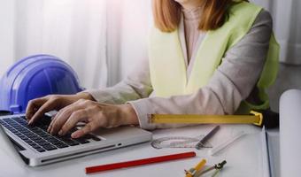 Zwei Kollegen diskutieren über Datenverarbeitung und Tablet, Laptop mit einem Architekturprojekt auf der Baustelle am Schreibtisch im Büro foto