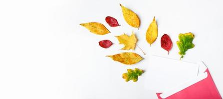 Herbst flach liegen. Umschlag mit einer leeren Grußkarte und gefallenen gelben Blättern auf weißem Hintergrund. foto
