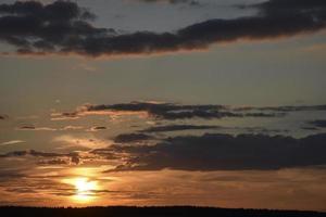 abendlicher blau-oranger Sonnenuntergang und ein schöner Horizont mit Wolken und Pflanzen. foto