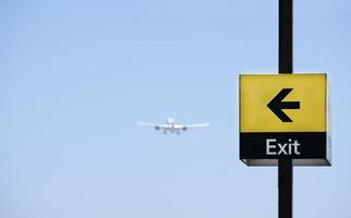 sich näherndes Flugzeug mit einem Schild mit der Aufschrift Ausfahrt, das darauf vor einem blauen Himmel zeigt foto