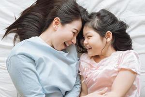 mutter und ihre tochter kind mädchen spielen im schlafzimmer .glückliche asiatische familie foto