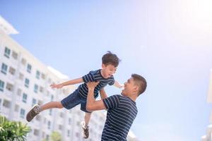 glücklicher vater und sohn spielen zusammen und haben spaß außerhalb der eigentumswohnung oder des mehrfamilienhauses. foto