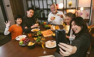 asiatische Familie, die vor dem Abendessen am Esstisch zu Hause ein Selfie macht foto