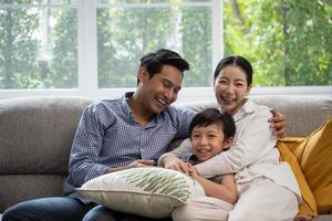 porträt einer glücklichen asiatischen familie, die zeit zusammen auf dem sofa im wohnzimmer verbringt. foto