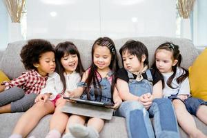Gruppe kleiner Kinder, die gemeinsam Zeichentrickfilme auf einem digitalen Tablet ansehen