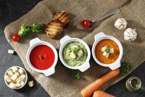 Dreifarbige Gemüsesuppe, Brokkoli, Tomate, Karotte auf schwarzem Marmortisch. foto