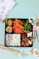 draufsicht japanische bento-brotdose mit gedämpftem gemüse, gekochtem ei, nugget, wurst, edamame und tempura.