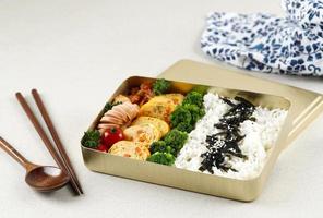 koreanische lunchbox dosirak, abgepackte mahlzeit bento lunchbox mit verschiedenen banchan, gyeran mari, tomate, brokkoli, kimchi und wurst. foto