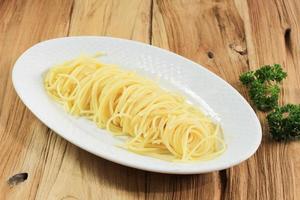 Spaghetti-Nudeln in einem ovalen weißen Teller isoliert auf Holzhintergrund foto