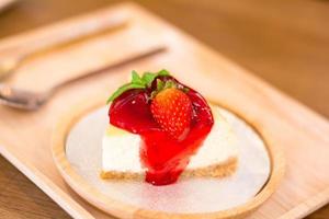 süßes dessert und bäckereikonzept. Strawberry Cheese Pie Cake auf einem weißen Teller auf einem weißen Teller auf einem Holztisch im Café.