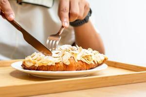 wüsten- und süßes bäckereikonzept. Croissant-Mandeln mit Messer und Frog auf einem weißen Teller in Cafés und Cafés essen.