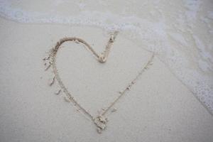 Herzen auf den Sand eines Strandes gezeichnet foto