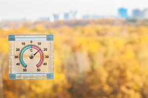 Thermometer am Fenster und unscharfer gelber Stadtpark foto