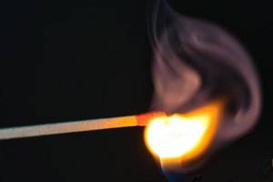 ein selektiver Fokus eines brennenden Streichholzes auf schwarzem Hintergrund foto