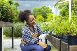 Die afroamerikanische Gärtnerin vernichtet ihre Blumenpflanze im Gärtnereizentrum für einheimische und exotische Pflanzenzüchter foto